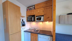 Eine kompakte Küche mit Holzschränken, einem Geschirrspüler, einer Mikrowelle und einem Toasterofen.