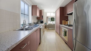 A modern kitchen with stainless steel appliances, a granite countertop, and a view to the living area.