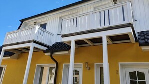 A two-story building with white balconies and yellow walls. - 2-room vacation apartment for 4 people on the 1st floor - with WLAN - NH (Ribnitz-Damgarten)