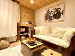 Ein gemütliches Wohnzimmer mit Kamin, einer Couch, einem Couchtisch aus Holz mit einer Schale und einem gerahmten Bild an der Wand.
