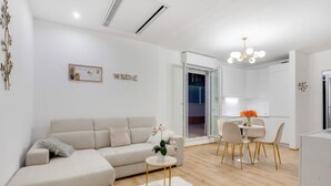 A modern living room with a sofa, a round coffee table, and a dining area with chairs and a table.