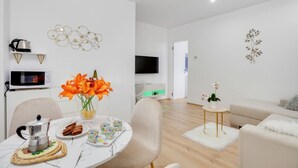 A modern living room with a round table, chairs, a sofa, a TV, and decorative wall art.