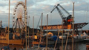 Un puerto deportivo con barcos amarrados, una noria y un letrero grande que dice 'ROSTOCKER'.