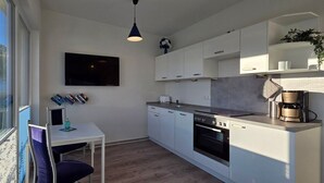 Una cocina moderna con armarios blancos, horno empotrado y cafetera.