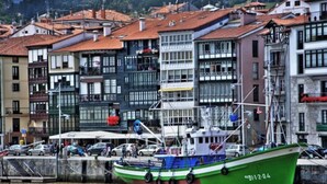 A green boat docked at a harbor with buildings in the background. - Piso Céntrico y Tranquilo en Gernika (Gernika-Lumo)
