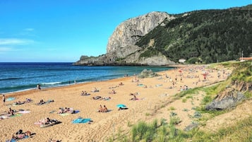 Enjoy a serene beach experience with calm seas and a scenic rock formation in the background.