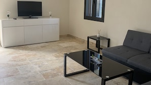 Un salon moderne avec un téléviseur à écran plat, un canapé, une table basse et un meuble.