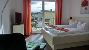 Une chambre d’hôtel avec un lit, une chaise, un bureau avec une lampe et une vue sur l’extérieur.