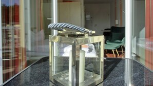 Une pièce comprenant une table en verre sur laquelle est exposé un objet métallique, une chaise et une porte donnant sur une autre pièce.