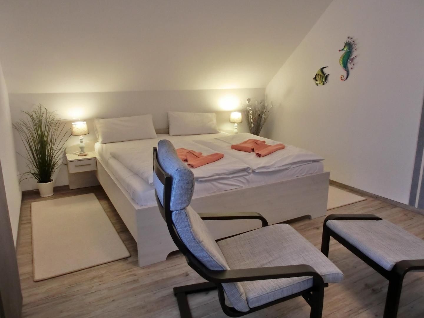 Ein modernes Schlafzimmer mit einem Bett, Nachttischen, einem Sessel und einem kleinen Tisch.