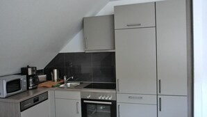 A compact kitchen with a microwave, coffee maker, and oven.