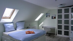 A bedroom with a bed, a desk, and a wardrobe.