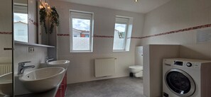 Ein modernes Badezimmer mit zwei Waschbecken, einer Toilette und einer Waschmaschine.