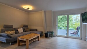 A modern living room with a grey sofa, a wooden coffee table, and a TV mounted on the wall. - Vacation apartment A3 - close to the beach - (84 m²) - three balconies and two (Graal-Müritz)
