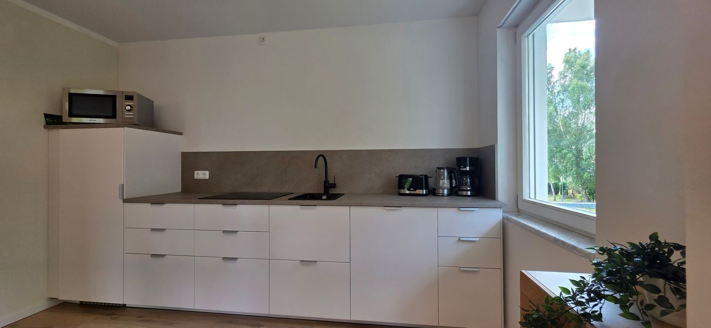 A compact kitchen with a microwave, sink, and coffee maker.