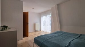 A bedroom with a bed, a radiator, and a door leading to another room. - Vacation apartment A3 - close to the beach - (84 m²) - three balconies and two (Graal-Müritz)