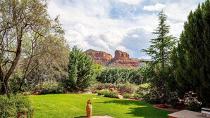 A garden with a concrete patio, green lawn, and a view of red rock formations. - Gated Historic Estate • Pool, Spa & Artifacts (Sedona)