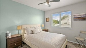 A bedroom with a bed, nightstands, a ceiling fan, a window with blinds, and a chair. - Charming Townhouse in the River Road Neighborhood - Pet friendly - Close to Downtown (Missoula)