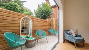 Una stanza accogliente con una terrazza in legno, una grande finestra e un divano blu.