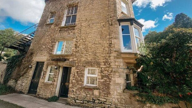 A stone building with a central entrance, a staircase, and a small balcony.