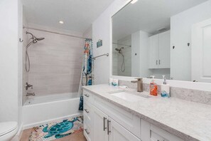 Een moderne badkamer met een bad, douche en een grote spiegel.