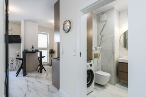 A modern bathroom with a marble floor, a washing machine, a toilet, and a sink.