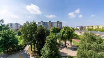 Ein Wohngebiet mit mehrstöckigen Wohngebäuden, einem Park mit Bäumen und einer Laufbahn, und einem strahlend blauen Himmel.