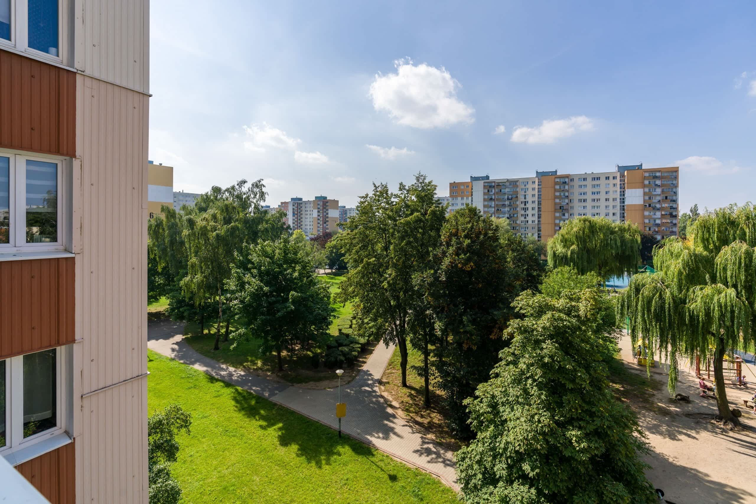 A residential building with a view of a park and other buildings in the background.
