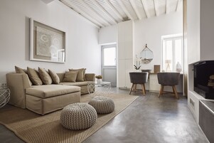 Una sala moderna con un sofá color beige, otomanas, una mesa de centro y un televisor.