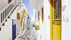 A narrow, white-walled alley with yellow doors and a blue door, leading to a staircase. - Crystal Green Signature Suites Mykonos (Mykonos)