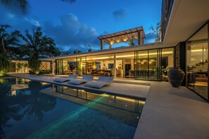 A modern house with a swimming pool, glass walls, and outdoor seating. - Villa BullHouse (Seminyak)