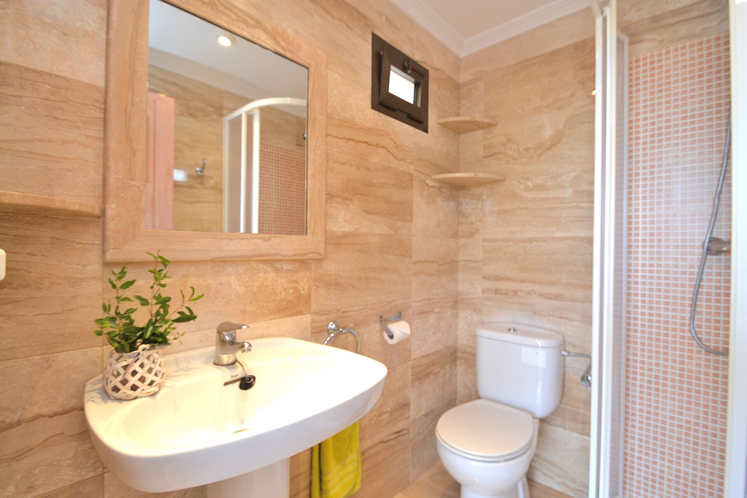 Een badkamer met een wastafel, spiegel, toilet en douche.