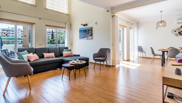 Un vaste espace de vie comprenant un canapé, des fauteuils, une table basse et un coin repas avec des chaises et une table.