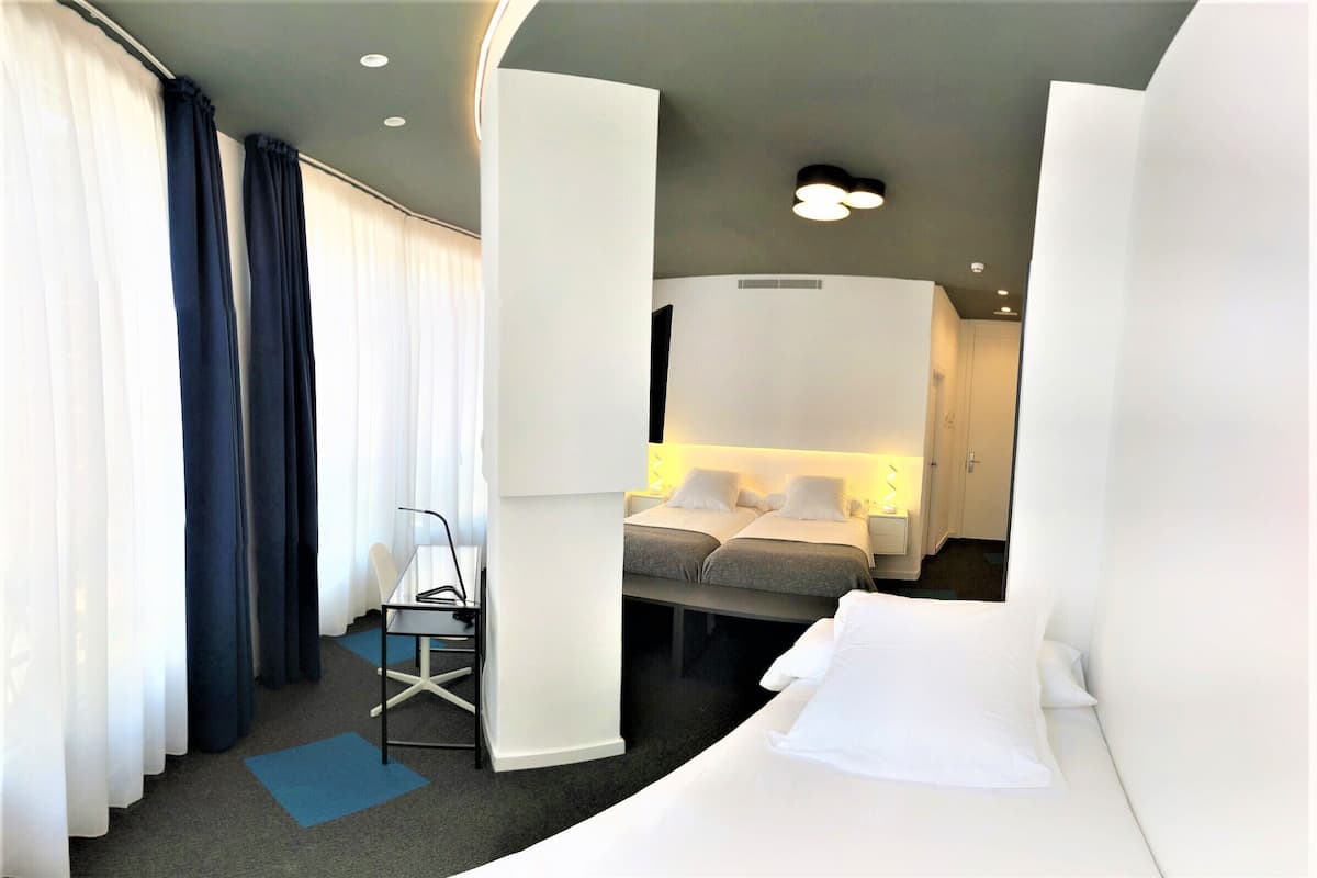 Una habitación de hotel con cama, mesita de noche y escritorio con silla.
