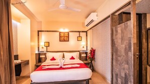 A hotel room with a bed, a ceiling fan, an air conditioning unit, and a wall with a patterned design. - Hotel Prabha Palace (Ahmednagar)