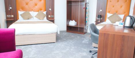 A hotel room with a bed, a desk, a chair, and a wardrobe.