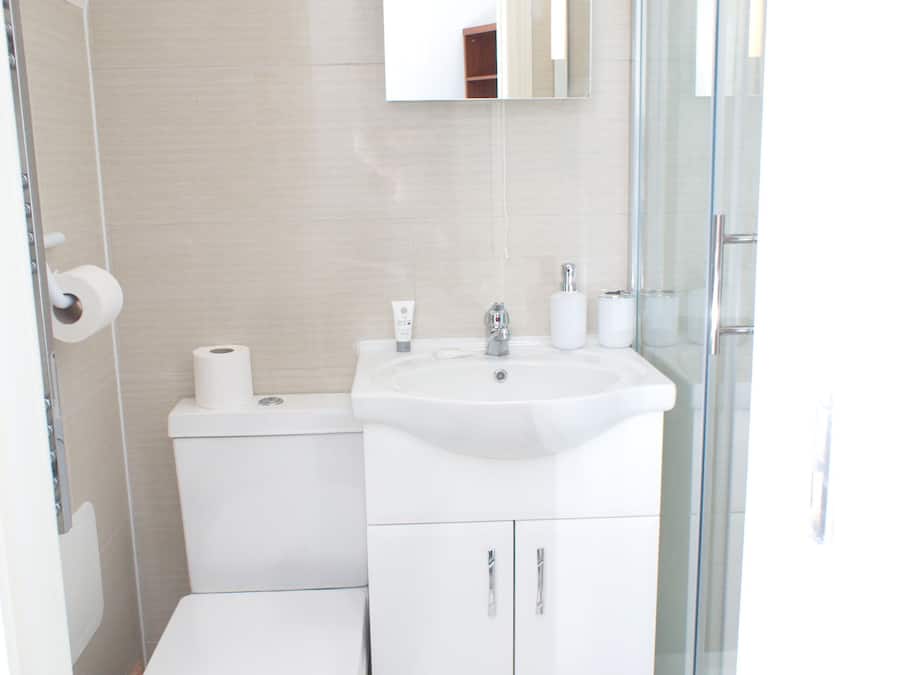 Un baño moderno con inodoro, lavamanos y espejo.