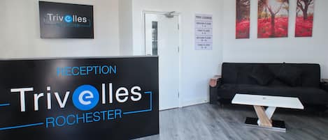 A reception area with a black reception desk labeled "Trivolles Rochester," a black sofa, and three red tree paintings on the wall.