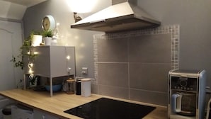 Et moderne køkken med en sort induktionskogetop, en indbygget ovn og en kaffemaskine.