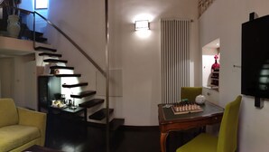 Ein Wohnzimmer mit Treppe, einer Couch, einem Tisch mit Schachspiel und einem Fernseher.