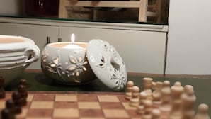 Ein Schachbrett mit Figuren, eine Kerze und Dekorationen auf einem Tisch.