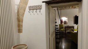 Ein Flur mit Heizkörper, Wandhakenleiste, einer Tür zu einem Essbereich mit Stühlen und Tisch sowie einer rustikalen Steinwand.