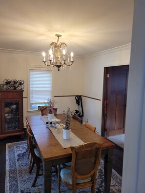 Enjoy meals in this dining area with a table for four, illuminated by a chandelier and natural light.