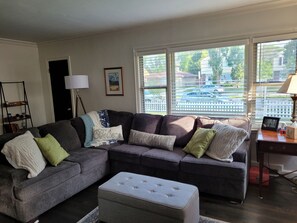 Relax in this stylish living room with a comfortable sofa, ottoman, and side table, offering a view of the surrounding neighborhood.