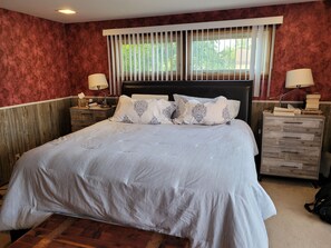 Relax in a cozy retreat with a large bed, wooden headboard, and a reading nook.