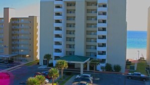 A hotel named Tropical Winds with a central entrance, multiple balconies, and a view of the ocean.