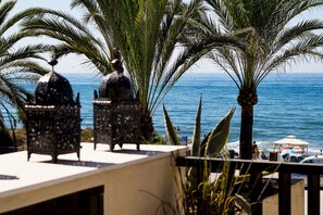 Terraza en la azotea con dos faroles decorativos, palmeras y vista al océano.