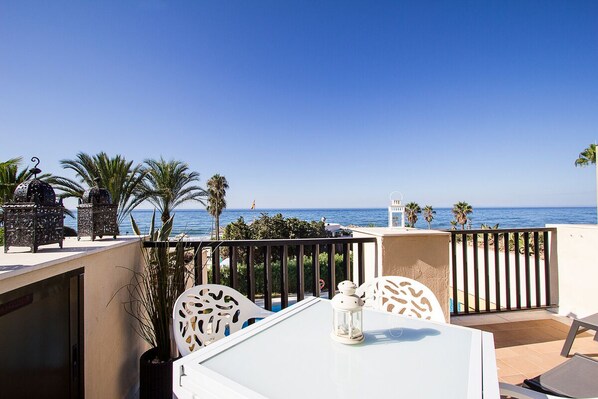 Une terrasse avec une table et des chaises, donnant sur la mer.
