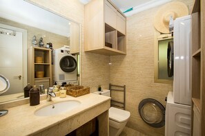 Une salle de bain moderne équipée d’un lavabo, d’un miroir, d’un lave-linge et de toilettes.