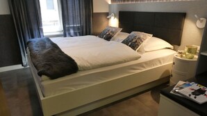 A modern hotel room with a bed, a bedside table, and a nightstand. - Zermatt Rental Venus Topfloor Apartment.  (Zermatt)